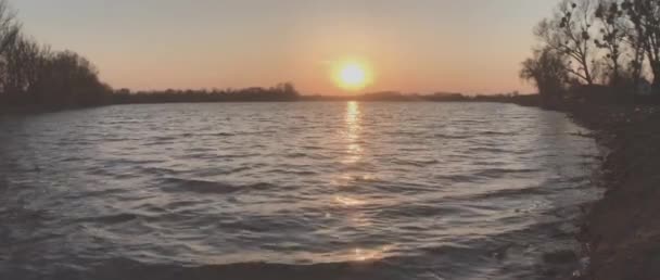 美丽的落日在平静的湖面上.太阳落在地平线上,波浪在海岸上飘扬.大自然的美、宁静、和平的概念. — 图库视频影像