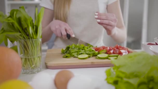 Mujer joven irreconocible cortando el dedo como ingredientes para rebanar ensalada. Chica delgada rubia caucásica que tiene un accidente mientras cocina alimentos saludables en el interior. Estilo de vida, dolor, herida, culinaria . — Vídeos de Stock