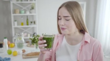 Bitkisel detoks kokteyli içen mutsuz beyaz kadın portresi. Suratı asık kız içeride diyet yapıyor. Ağırlık kontrolü, öz disiplin, sağlık hizmetleri, sağlıklı yaşam tarzı..