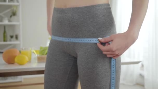 用带子测量年轻女子臀部的特写。瘦小的白人女孩控制着体重和幸福。健康生活方式、节食、运动、美容标准的概念. — 图库视频影像