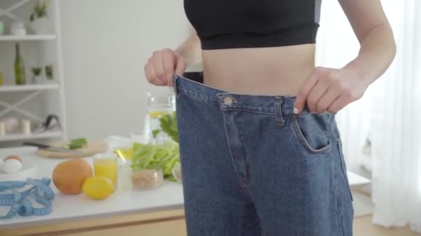 Mujer delgada joven irreconocible en jeans grandes. Chica caucásica delgada mostrando pérdida de peso. Deporte, estilo de vida saludable, alimentación saludable, estándar de belleza . — Vídeo de stock