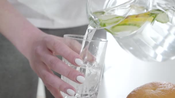 Langzame beweging van onherkenbare vrouw die water in glas giet en detox cocktail drinkt. Jonge blanke vrouw die eet en voor haar gezondheid zorgt met biologische drank. Lifestyle. Langzaam. — Stockvideo