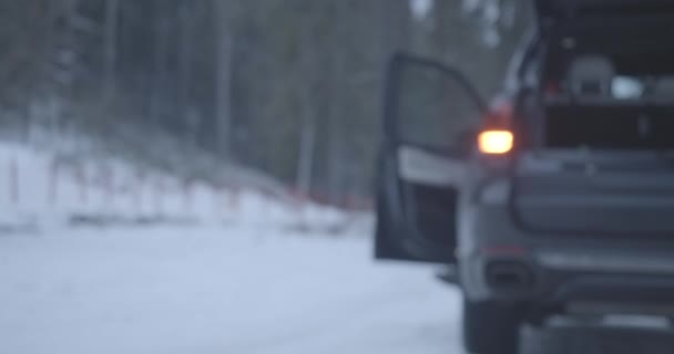 道路の安全性のベストを取り、カメラに近づいて、車のフードを開く白人の女性がぼやけている。雪道で壊れた自動車と認識できない女性ドライバー。シネマ4k｜ProRes HQ. — ストック動画
