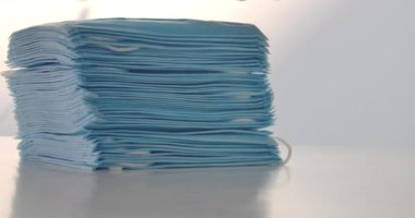 Masadaki yığına beyaz el koruyucu yüz maskeleri ekliyor. Tanınmayan doktor ya da gönüllü Covid-19 salgınından muzdarip insanlar için tıbbi maske topluyor. Sinema 4k ProRes Merkezi.