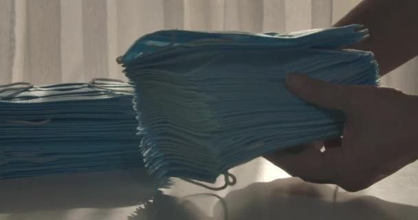 Female hands flipping through protective medical masks and putting stack on the table. Unrecognizable Caucasian woman with antiviral face masks. Covid-19, virus, epidemic. Cinema 4k Prores HQ. — Stock Video