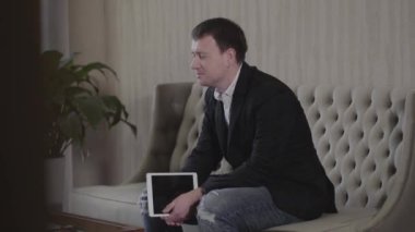 Kendine güvenen, tabletli beyaz bir adam konuşuyor ve bilinmeyen bir adamı dinliyor. Meslektaşlarıyla proje tartışan ya da iş görüşmesi yapan profesyonel iş adamının portresi. İş dünyası.