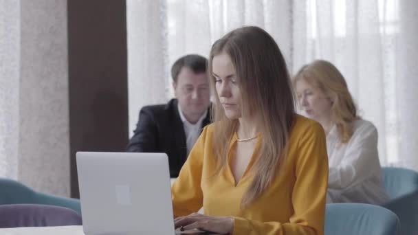 Portret poważnej brunetki rasy kaukaskiej zamykającej laptopa i trzymającej głowę rękami. Zmęczona piękna bizneswoman pracująca w kawiarni z ludźmi rozmawiającymi w tle. Styl życia, przepracowanie. — Wideo stockowe