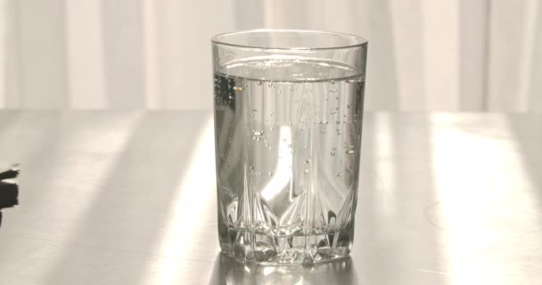 Goutte de pilule soluble dans un verre d'eau transparente. Médicament se dissolvant dans le liquide. Gros plan. Concept de soins de santé, médecine, médicaments, pharmacie. Siège social Cinema 4k ProRes . — Video