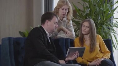 Profesyonel ekip tablet ekrana bakıyor ve projeyi tartışıyor. Yetişkin beyaz erkek ve kadınlar dijital iş sunumu yapıyor. İşbirliği, yaşam tarzı, takım çalışması, başarı.