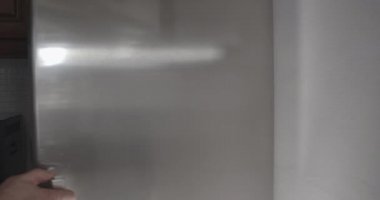 Beyaz bir erkek el gri buzdolabını açıyor, çöreği alıp gidiyor. İçeride yemek yiyen tanınmayan yetişkin bir adam. Sinema 4k ProRes Merkezi.