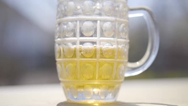 Giet verfrissend schuimig pilsbier in glas. Close-up van bierglas dat in het zonlicht buiten staat. Alcoholindustrie, rust, ontspanning, drank. — Stockvideo