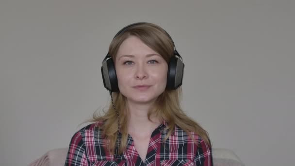 Retrato de chica caucásica sonriente en auriculares diciendo adiós a los colegas o amigos que utilizan el chat en línea. Mujer linda joven saludando a la cámara. Trabajo remoto, estilo de vida, reuniones, tecnología inalámbrica . — Vídeo de stock