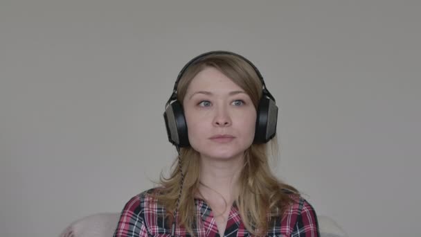 Egy fiatal, csinos nő portréja nem ért egyet a kamerával. Kaukázusi lány fülhallgatóban, kollégákkal beszélget az online chaten. Üzleti megbeszélések a Covid-19 lezárásáról, koronavírus karantén. életmód. — Stock videók