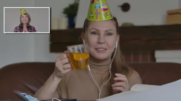 즐거운 백인 여성 두 명 이 파티 모자를 쓰고 비디오 채팅으로 축하하고 있습니다. Covid-19 격리 구역에서 온라인에서 웃고 수다떠는 긍정적 인 소녀. 코로나 바이러스 차단, 원격 통신, 생활 방식. — 비디오