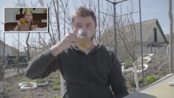 Alegre caucásico hombre y mujer celebrando fiesta en el chat en línea. Sonriente chico con cerveza lager y alegre mujer con taza de té tintineo selfie cámaras y beber. Celebración remota, bloqueo de Covid-19 — Vídeos de Stock