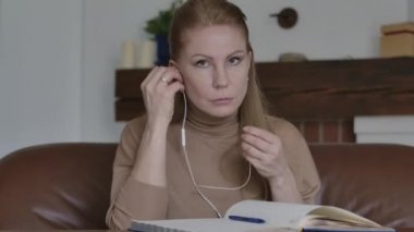 Güzel beyaz kadın portresi kulaklık takıyor, kameraya el sallıyor ve gülümsüyor. İnternette genç bayan görüntülü konuşma yapıyor. Uzak çalışma, iş, Covid-19 yaşam tarzı.