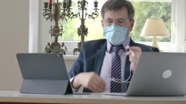 İş adamının portresi kulaklıkları, yüz maskesi ve gözlükleri çıkarıp gidiyor. Kravatlı, ceketli ve uyku pantolonlu rahat bir adam internette sohbet ediyor. Uzaktan kumanda, Covid-19 tecrit.
