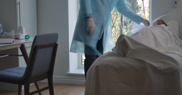 Мужчина-европеолог приходит к пациентке с кашлем, лежащей на кровати, проверяя оборудование на механическую вентиляцию. Медицинский работник, ухаживающий за больной женщиной, страдающей от Ковид-19. Штаб-квартира кинотеатра 4k ProRes . — стоковое видео