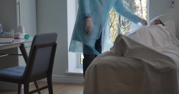 Manlig kaukasisk läkare kommer till hosta kvinnlig patient liggande på sängen, kontrollutrustning för mekanisk ventilation. Läkare som tar hand om sjuka kvinnor som lider av Covid-19. Bio 4k ProRes HQ. — Stockvideo