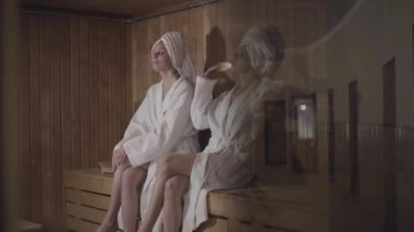 Başarılı iş kadınları spa 'da oturup konuşuyorlar. Hafta sonları ya da tatillerde dinlenen iki beyaz kadının portresi. Koyu cam kapının arkasında ateş ediyorlar. Boş zaman, rahatlama, yaşam tarzı, lüks..