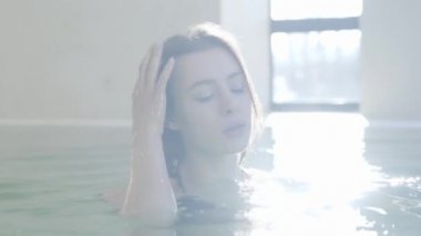 Sabah yüzme havuzunda cesedi yıkayan kendine güvenen genç bir kadının yakın çekimi. Güneş ışığında kahverengi gözlü, esmer, beyaz bir kızın portresi. Boş zaman, rahatlama, yaşam tarzı..