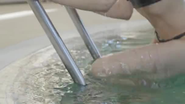 Close-up of unrecognizable slim Caucasian woman getting out of swimming pool. Long slender female legs stepping on pool stairs and leaving. Girl in black bikini resting in spa hotel. — Stock Video