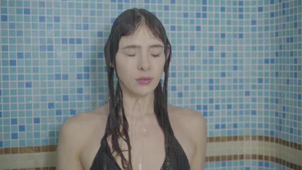 性感的年轻黑发女子站在自来水下的特写脸。穿着比基尼泳衣洗澡的漂亮白人女孩的画像。休闲、身体护理、生活方式、美. — 图库视频影像