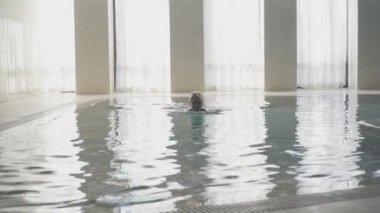 Kendine güvenen genç bir kadının portresi. Havuzdan çıkıp gidiyor. Sabahları evde yüzen zayıf, yetişkin, beyaz bir bayan. Yaşam tarzı, spor, eğlence..