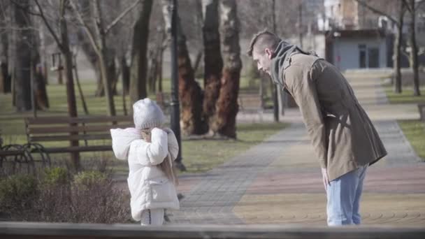 Widok z boku młodego białego mężczyzny besztającego dziewczynkę w jesiennym parku. Zdenerwowany ojciec wrzeszczący na płaczącą córkę i gestykulujący. Konflikt, problem, nieposłuszeństwo, smutek. — Wideo stockowe