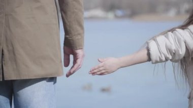 Küçük beyaz bir kadın ırmağın arka planında babasının elini tutuyor. Tanımlanamayan esmer, kıvırcık saçlı, nehir kıyısında ailesiyle birlikte durup ördekleri izleyen kız. Ebeveynlik, birlik.