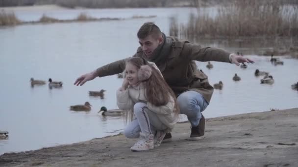 Alegre caucásico hombre y chica mirando a patos e imitando volar. Retrato de feliz padre joven y bonita hija disfrutando los fines de semana al aire libre. Felicidad, familia, alegría, ocio . — Vídeos de Stock