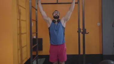 Spor salonundaki yakışıklı Orta Doğulu adamın antrenmanı. Güçlü sakallı sporcu parmaklıklara asılıp bacaklarını kaldırıyor. Spor kulübü, sallanan bacaklar, zindelik, sağlıklı yaşam tarzı..