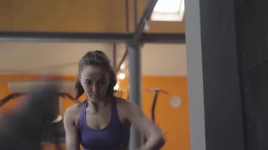Çapraz formda halat kullanan ciddi bir sporcunun portresi. Spor salonunda egzersiz yapan güzel beyaz bir kadın. Spor, güç, egzersiz, sağlıklı yaşam tarzı..