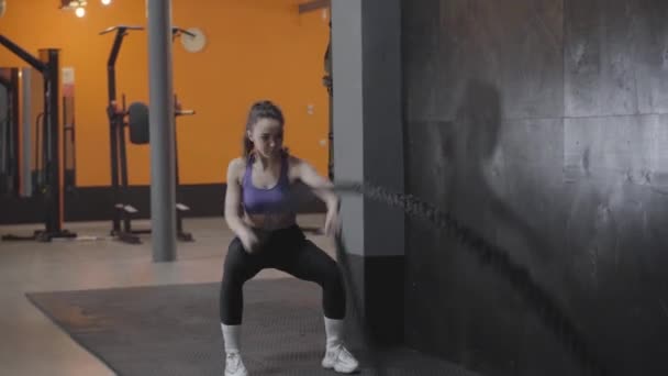Ευρεία βολή της ισχυρής νεαρής Καυκάσιας γυναίκας να κάνει ασκήσεις με σχοινιά. Η Μπρουνέτ προπονείται στο γυμναστήριο. Υγιεινός τρόπος ζωής, αθλητισμός, προπόνηση, γυμναστική. — Αρχείο Βίντεο