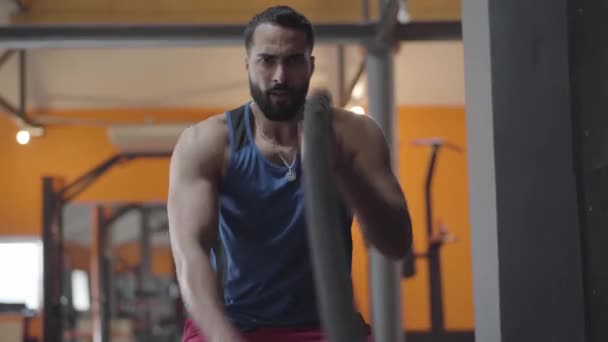 Vista frontal de un joven deportista serio que termina el ejercicio crossfit. Hombre barbudo de Oriente Medio entrenando en gimnasia. Deporte, salud, estilo de vida, tensión . — Vídeos de Stock