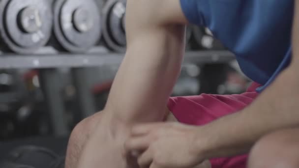 Detailní záběr mužských bicepsů. Nerozpoznatelný mladý muž zvedající činky. Svalová stavba, vytrvalost, síla, mužnost. — Stock video