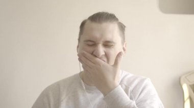 Esmer, beyaz bir adam internette iş arkadaşlarını dinliyormuş gibi esniyor. Uzaktan kumandada kahverengi gözlü yakışıklı bir gencin portresi. Serbest, tecrit. S-seyir defteri 2, QuickTime ProRes 422 HQ.