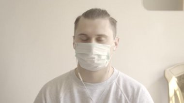 Yüz maskeli genç adam görüntülü sohbette biriyle aynı fikirde. Kahverengi gözlü esmer beyaz adamın portresi. Covid-19 'da evden çalışıyor. S-seyir defteri 2, QuickTime ProRes 422 HQ.