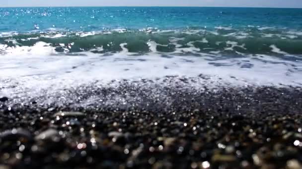 Turquesa ondas marinhas espumosas rolando em seixos na praia. Vista frontal da costa do Mar Mediterrâneo de Chipre sob o sol. Dia ensolarado no resort tropical. Natureza, beleza, ambiente . — Vídeo de Stock