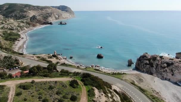 Vue par drone du lagon méditerranéen entre les collines rocheuses de Chypre. Vue aérienne des eaux calmes de la mer roulant sur la plage de galets avec des gens marchant le long du bord de mer. Nature, paysage marin, station balnéaire . — Video