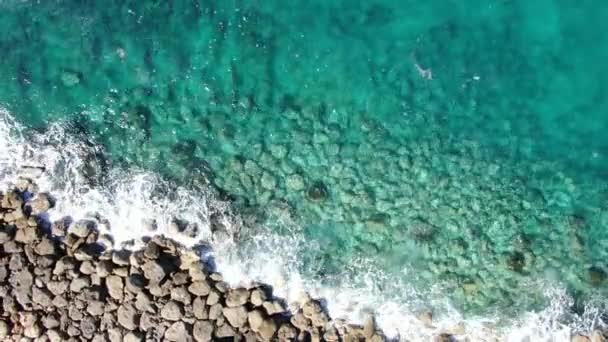 Turkoois transparant water spat over rotsen in de oceaan. Bovenaanzicht vanuit de lucht van schuimige kristalheldere golven van de Middellandse Zee op Cyprus. Zeegezicht, omgeving, schoonheid in de natuur, toeristische plaats. — Stockvideo