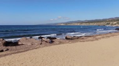 Akdeniz 'in kumlu sahili. Koyu mavi dalgalar güneş ışınlarına karışıyor. Güneşli bir günde Kıbrıs Rum Kesimi turizm beldesinin geniş açılımı. Turizm, tatiller, doğa, güzellik, deniz manzarası.