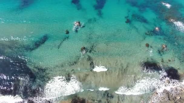 Cámara siguiendo olas espumosas turquesas rodando en la playa de arena con guijarros. Vista aérea de la hermosa costa del mar Mediterráneo en Chipre resort. Naturaleza, turismo, belleza, paisaje marino . — Vídeos de Stock