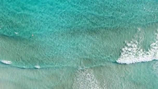 Kamera folgt türkisfarbenen Wellen des Mittelmeeres. Blick von oben auf schäumendes Wasser, das sich am Sandstrand des zyprischen Resorts wälzt. Meereslandschaft, Natur, Tourismus, Urlaub. — Stockvideo
