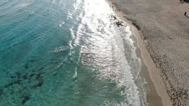 Drone se move ao longo da praia de areia e ondas turquesa do Mar Mediterrâneo ao pôr do sol. Vista aérea da natureza paradisíaca lindo em Chipre resort no pôr do sol. Turismo, paisagem marinha, natureza, férias . — Vídeo de Stock