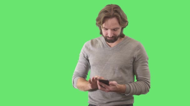 Porträt eines selbstbewussten brünetten kaukasischen Mannes, der Nachrichten auf seinem Smartphone tippt. Junger gutaussehender Typ, der soziale Medien am Telefon nutzt. Lebensstil, drahtlose Kommunikation. Green Screen, chromakey. — Stockvideo