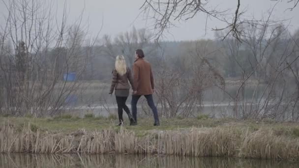 Breed shot van volwassen man en vrouw wandelen langs de rivier of het meer op het platteland. Zelfverzekerd blank stel dat dag in dag uit buiten doorbrengt. Liefdevolle man en vrouw die lopen en praten. Liefde, vrije tijd, levensstijl. — Stockvideo