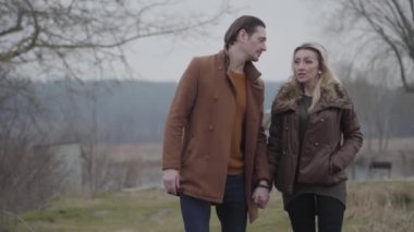 Sevgi dolu bir adamın ciddi bir kadınla flört etmesi ve elini öpmesi. Bulutlu bir günde güzel sarışın bir bayanla çıkan kendinden emin esmer beyaz adamın portresi. Aşk, flört, romantizm.