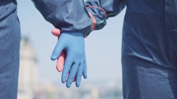 Detailní záběr nerozpoznatelného muže a ženy v ochranných rukavicích držících se za ruce. Milující pár datování během Covid-19 pandemie nebo globální znečištění. Jednota, láska, hazard, radiace.