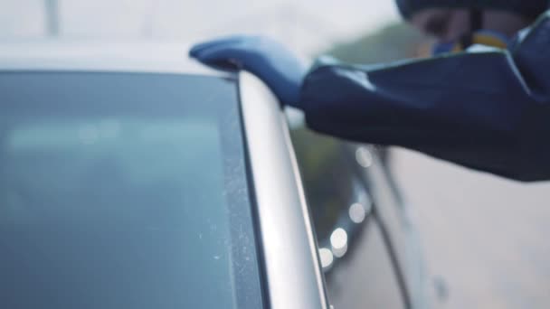 Homme caucasien en respirateur et costume bleu risque biologique regardant dans la voiture d'argent par la fenêtre latérale. Gros plan des travailleurs flous qui consultent les conducteurs sur les routes de la ville. Covid-19 quarantaine, pollution radioactive . — Video